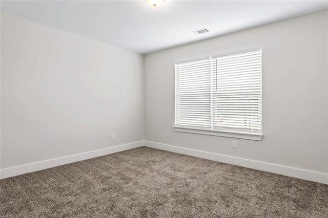 carpeted empty room with baseboards, a wealth of natural light, and visible vents