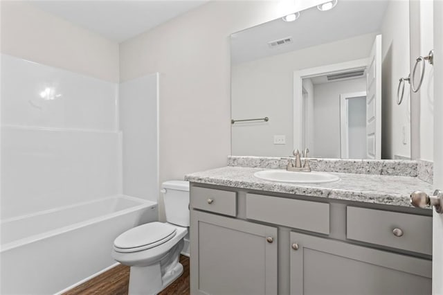 full bath with visible vents, vanity, shower / bathtub combination, wood finished floors, and toilet
