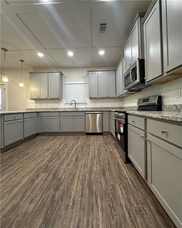 kitchen with visible vents, gray cabinetry, dark wood finished floors, stainless steel appliances, and a sink