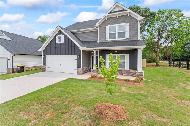 craftsman inspired home with covered porch, stone siding, a front yard, board and batten siding, and concrete driveway