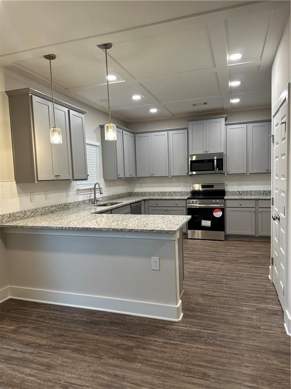 kitchen featuring dark wood-style floors, a peninsula, a sink, gray cabinetry, and appliances with stainless steel finishes