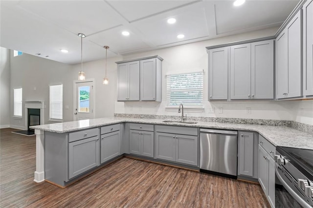 kitchen with appliances with stainless steel finishes, dark wood finished floors, gray cabinetry, a sink, and a peninsula