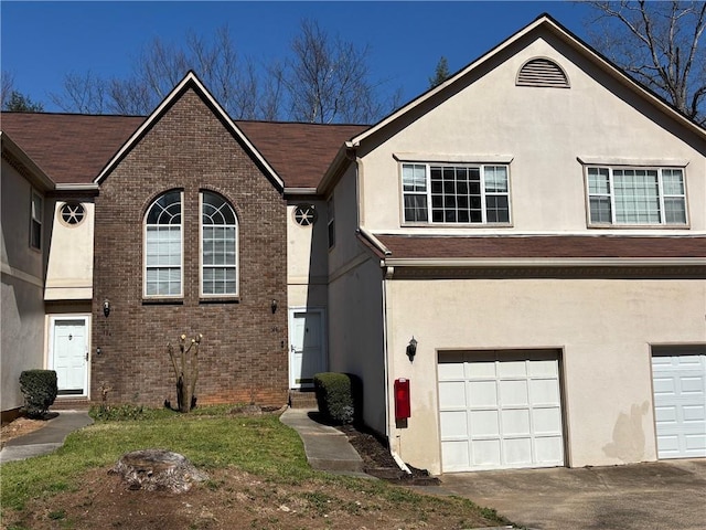 view of front of property featuring brick siding, stucco siding, driveway, and a garage