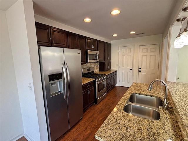 kitchen with tasteful backsplash, dark wood-type flooring, dark brown cabinetry, appliances with stainless steel finishes, and a sink