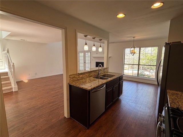 kitchen featuring light stone counters, a fireplace, a sink, dark wood-type flooring, and appliances with stainless steel finishes