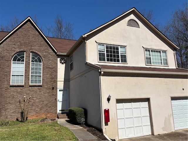 view of front of home featuring brick siding, stucco siding, and an attached garage