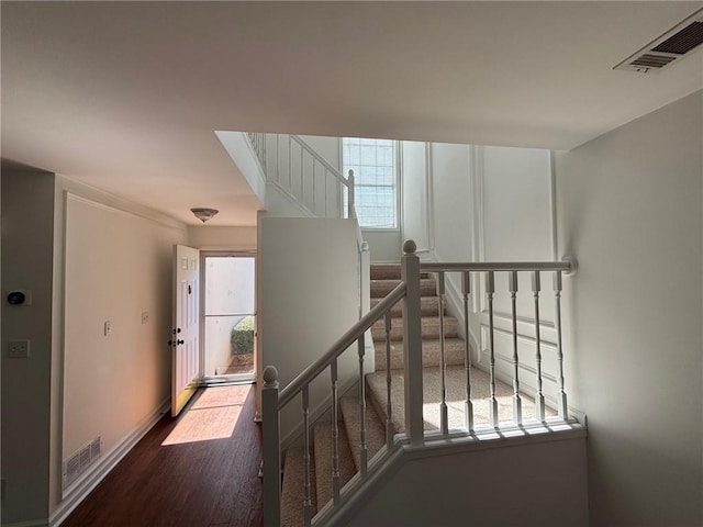 stairs featuring visible vents, baseboards, and wood finished floors