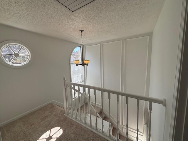 stairway with carpet flooring, baseboards, and a textured ceiling