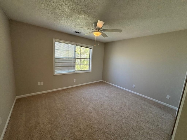 carpeted spare room featuring visible vents, ceiling fan, a textured ceiling, and baseboards