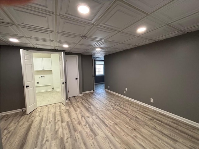 below grade area with light wood-type flooring, baseboards, an ornate ceiling, and recessed lighting