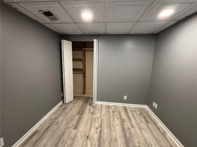 unfurnished bedroom with a closet, visible vents, light wood-type flooring, and baseboards