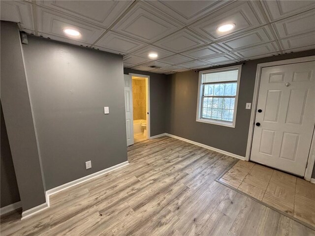 interior space featuring baseboards, an ornate ceiling, and light wood-style flooring