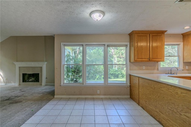 1615 Burnt Oak Way, Dacula, GA 30019 - kitchen with light countertops, light tile patterned flooring, a fireplace, brown cabinets, and a textured ceiling