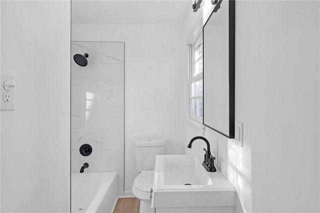 full bathroom with toilet, a healthy amount of sunlight, hardwood / wood-style flooring, and tiled shower / bath combo