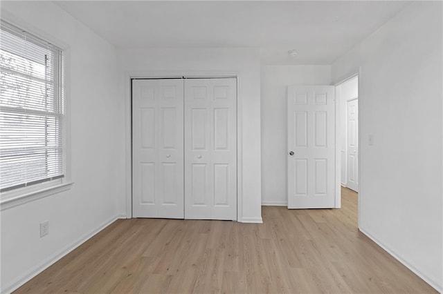 unfurnished bedroom featuring multiple windows, a closet, and light wood-type flooring