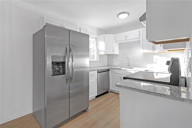 kitchen with appliances with stainless steel finishes, sink, white cabinets, light wood-type flooring, and light stone counters