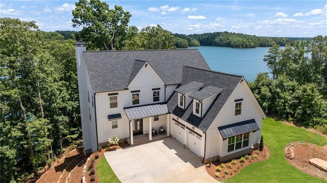 modern inspired farmhouse with a water view, a front lawn, and a garage