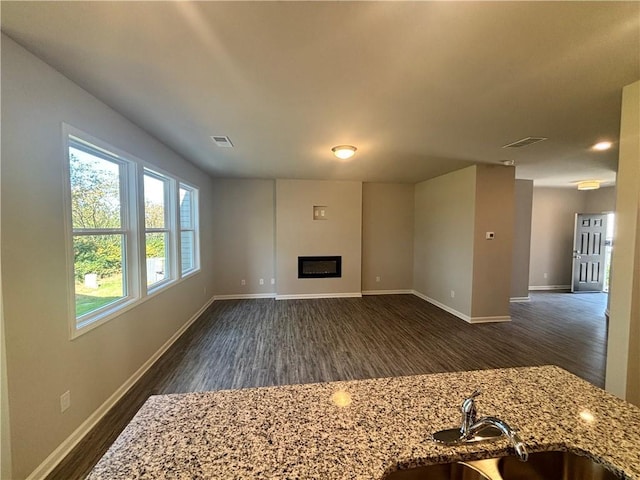 unfurnished living room featuring sink and dark wood-type flooring