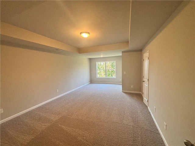 carpeted spare room featuring a tray ceiling