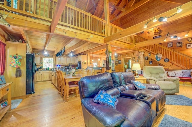 living room with beamed ceiling, light hardwood / wood-style floors, wood walls, and wood ceiling