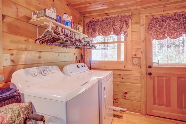 clothes washing area featuring wooden ceiling, separate washer and dryer, light hardwood / wood-style flooring, and wooden walls