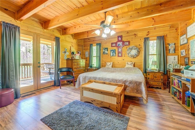 bedroom with access to exterior, french doors, ceiling fan, and wooden walls