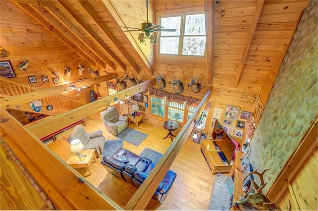 living room with wooden walls, light hardwood / wood-style floors, ceiling fan, and wooden ceiling