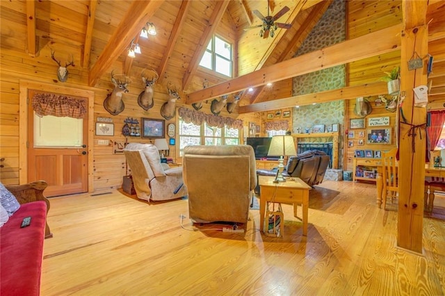 living room featuring high vaulted ceiling, wooden walls, ceiling fan, beam ceiling, and light hardwood / wood-style floors