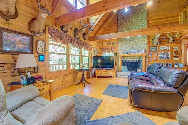 living room with beam ceiling, a stone fireplace, high vaulted ceiling, wood walls, and hardwood / wood-style floors