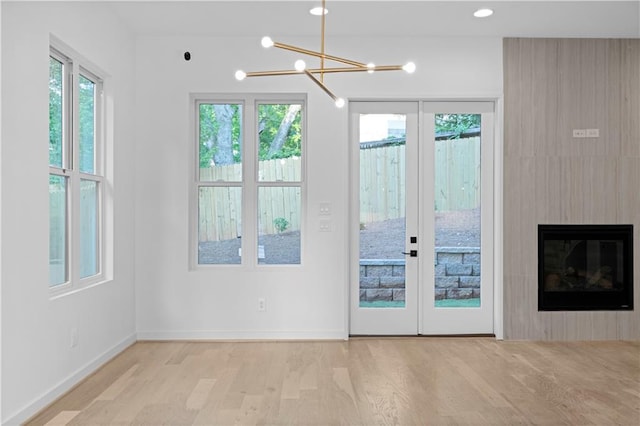 entryway featuring a notable chandelier, french doors, a fireplace, and light hardwood / wood-style flooring