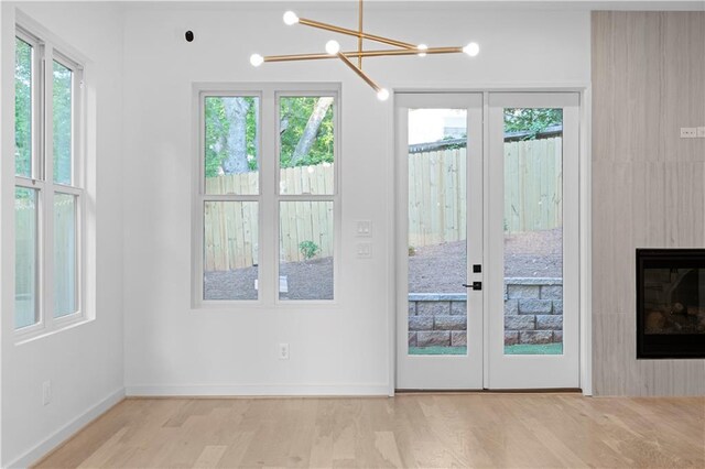 doorway featuring a fireplace, light hardwood / wood-style floors, and an inviting chandelier