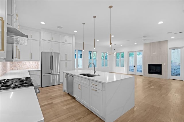 kitchen with hanging light fixtures, sink, an island with sink, and appliances with stainless steel finishes