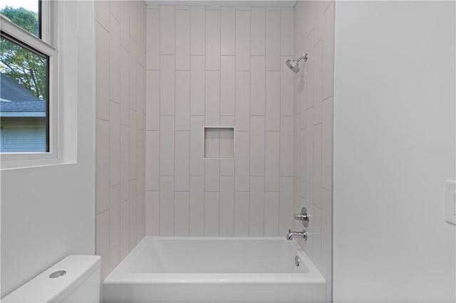 bathroom with toilet and tiled shower / bath