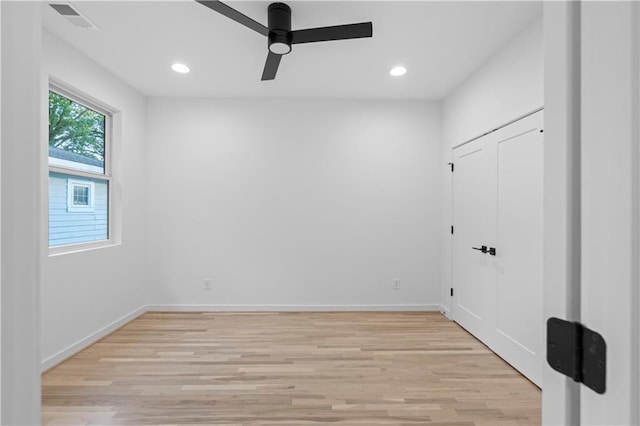 empty room with ceiling fan and light hardwood / wood-style flooring