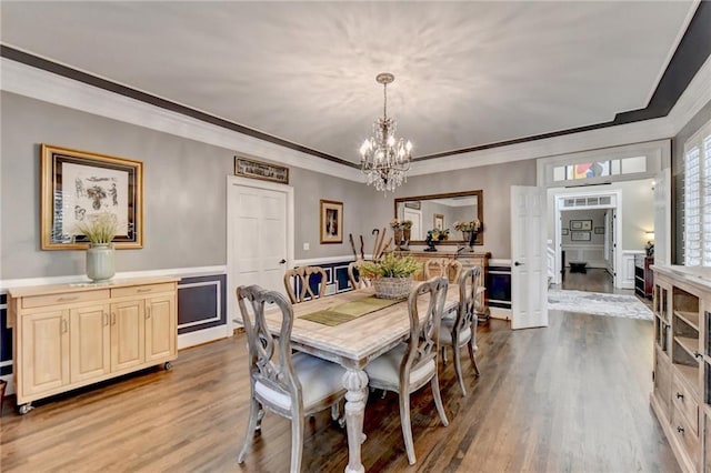 dining area with a wealth of natural light, dark hardwood / wood-style floors, ornamental molding, and an inviting chandelier