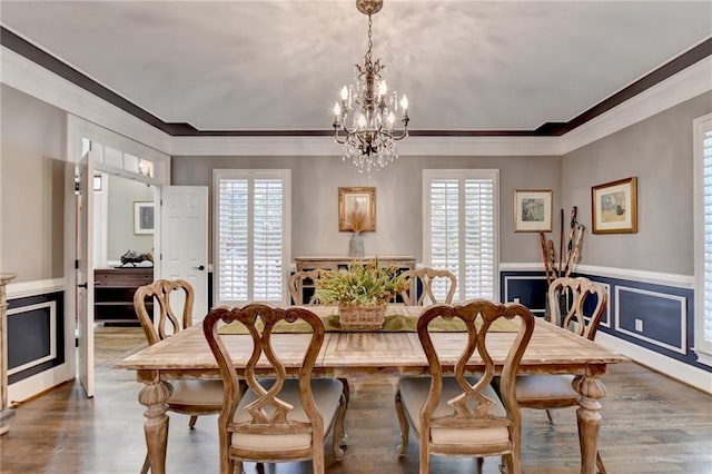 dining area with hardwood / wood-style floors, crown molding, and a notable chandelier