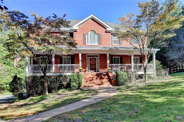 view of front of house featuring brick siding, covered porch, and a front yard