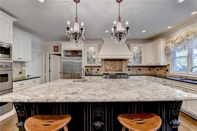 kitchen featuring white cabinetry, stainless steel appliances, custom range hood, and light stone counters