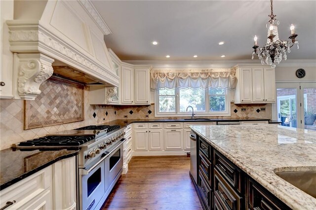 kitchen with sink, decorative light fixtures, decorative backsplash, dark stone counters, and a chandelier