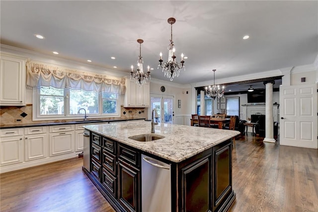 kitchen with sink, stainless steel dishwasher, dark stone countertops, and ornate columns