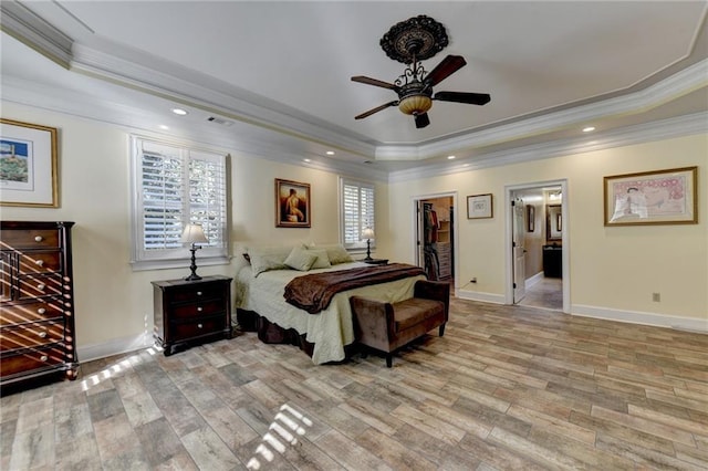 bedroom featuring ceiling fan, crown molding, light hardwood / wood-style floors, and a tray ceiling