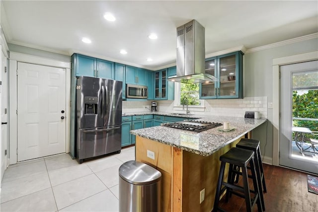 1192 Eastridge Rd SW, Atlanta, GA 30311 - kitchen featuring blue cabinetry, light stone counters, kitchen peninsula, island exhaust hood, and stainless steel appliances