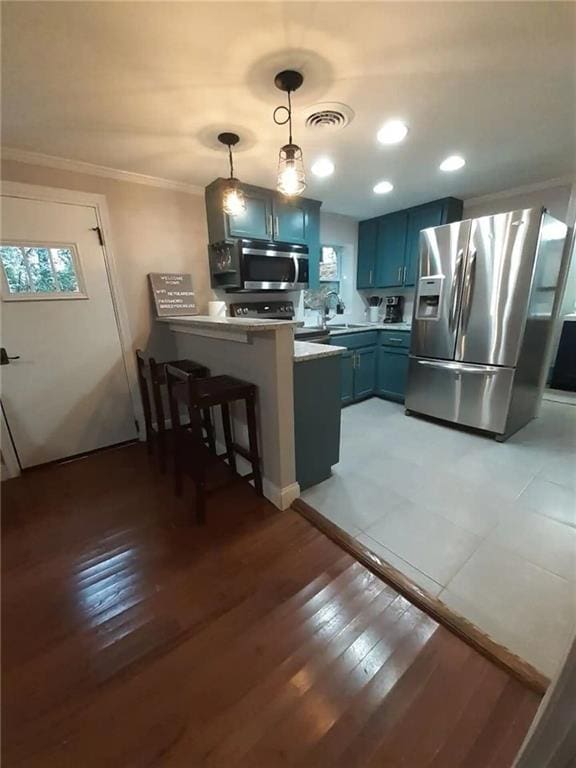 1192 Eastridge Rd SW, Atlanta, GA 30311 - kitchen with a breakfast bar area, appliances with stainless steel finishes, hanging light fixtures, blue cabinets, and kitchen peninsula
