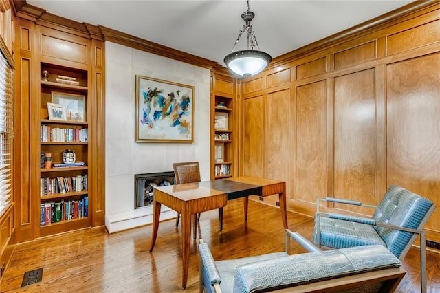 office featuring crown molding, built in shelves, and light hardwood / wood-style flooring