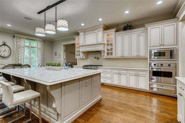 kitchen with pendant lighting, stainless steel appliances, a kitchen breakfast bar, tasteful backsplash, and light wood-type flooring