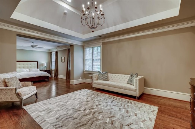 bedroom with a raised ceiling, dark hardwood / wood-style flooring, and an inviting chandelier