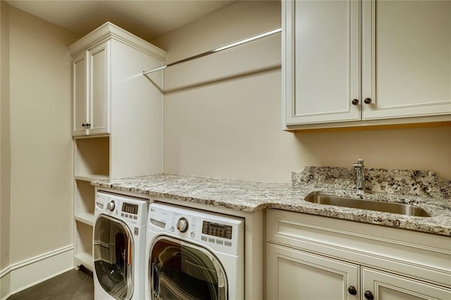 washroom with dark tile flooring, washing machine and clothes dryer, cabinets, and sink