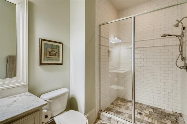 bathroom featuring toilet, a shower with shower door, and vanity