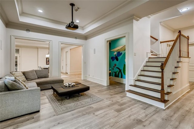 living room featuring a tray ceiling, ornamental molding, and light hardwood / wood-style flooring