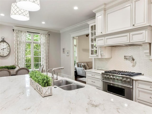 kitchen featuring pendant lighting, sink, light stone counters, tasteful backsplash, and stainless steel stove